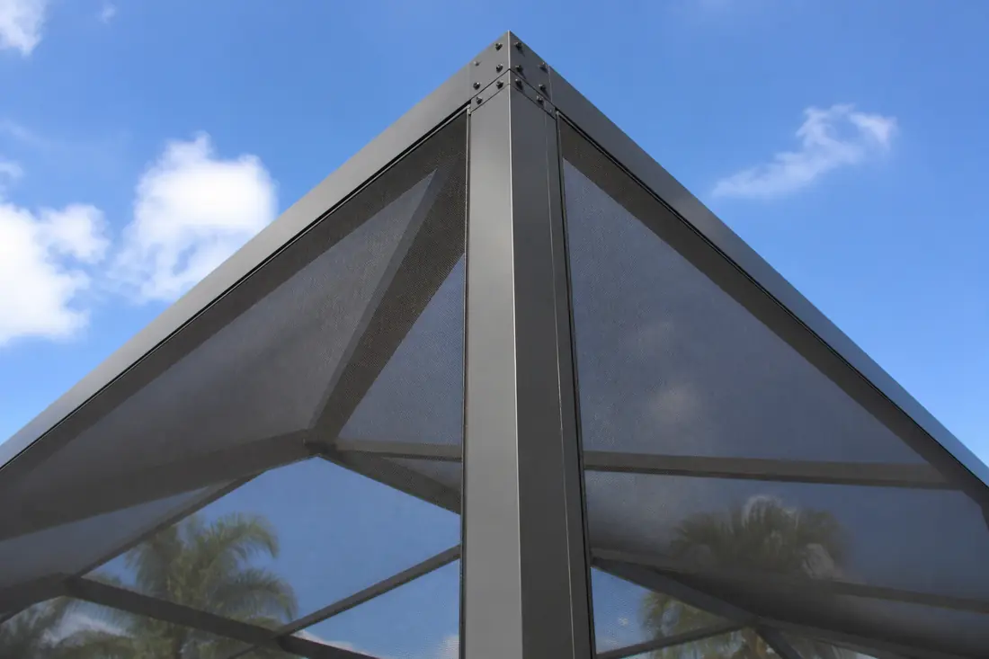The corner upright of a large screen enclosure seen from below against the sky